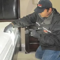 Bed bug inspection technician checking a mattress and bed frame for signs of infestation in Miami, FL